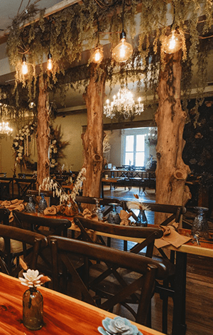 The BoHo before guests arrive — live-edge tables, birch columns, Spanish moss and Edison bulbs