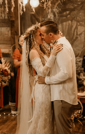 Bride and groom holding each other in the BoHo, warm light and dried florals around them