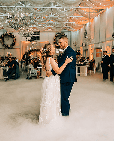 First dance in a low cloud of dry ice, guests watching from the tables